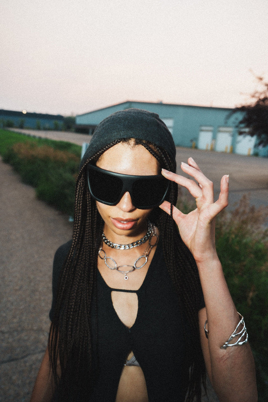 Model in a black beanie and oversized sunglasses outdoors at golden hour
