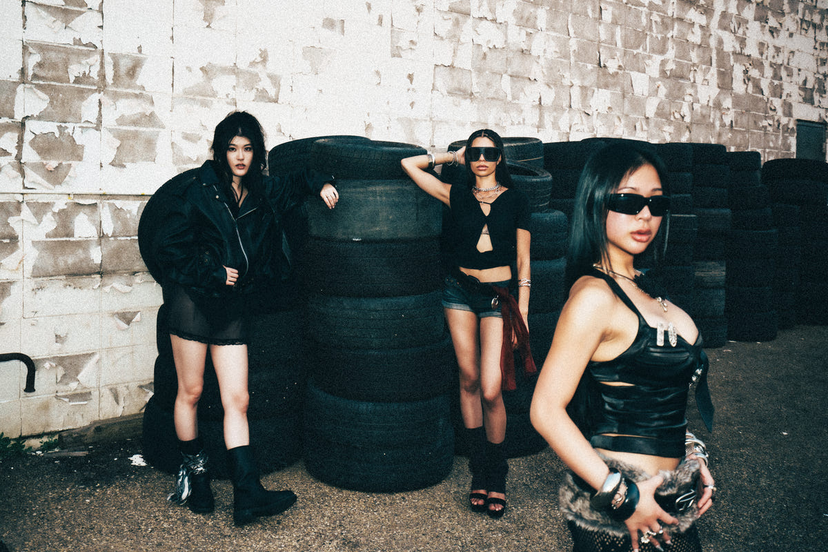 Three LATENIGHTLIPS models posing by an industrial tire wall.