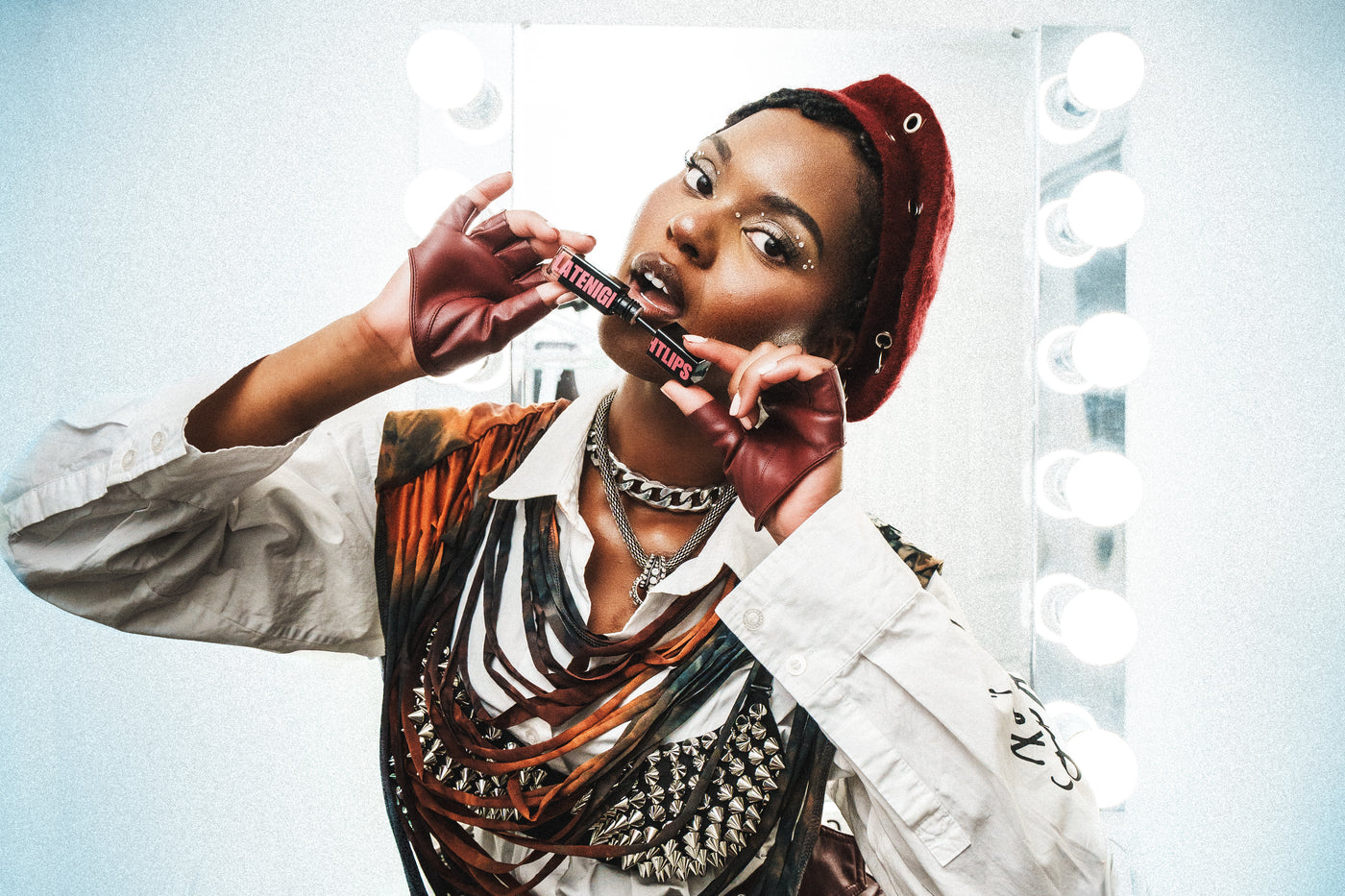 Model in a red beret holding Butter'd Up lip gloss