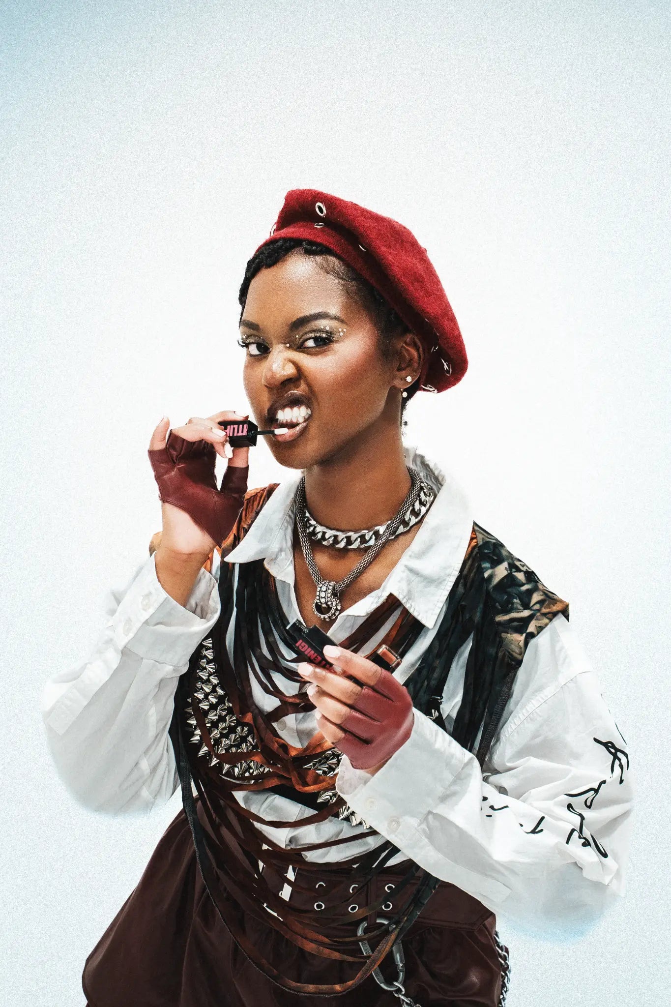 Nyssa in a red beret holding the Butter'd Up tube in a beauty portrait.